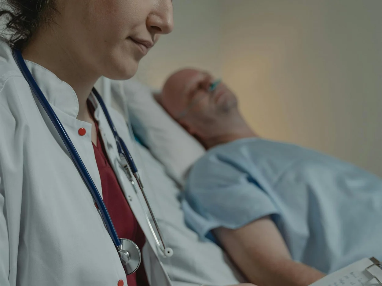 Clinician taking notes at the bedside of a resting patient