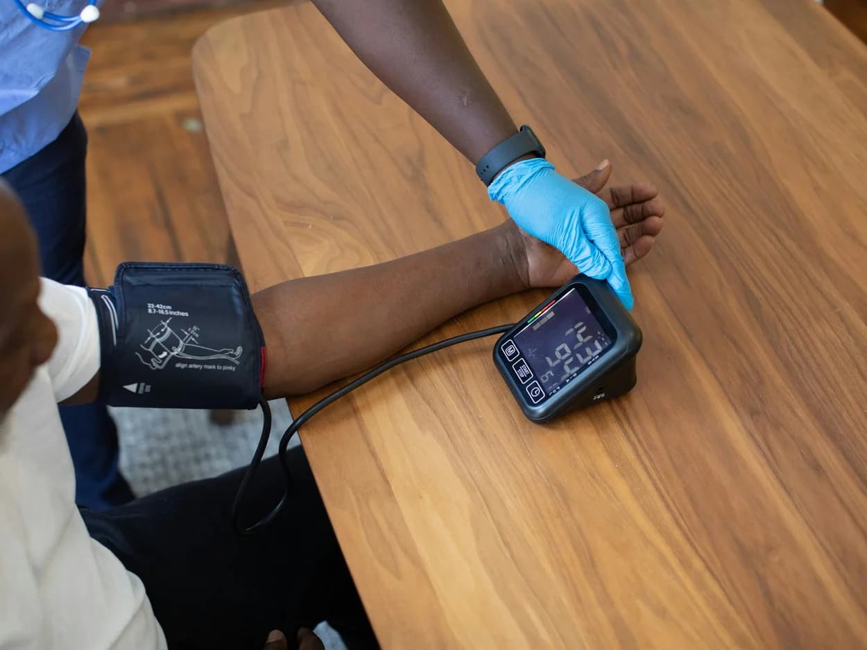 Gloved clinician taking a blood pressure reading at a kitchen table